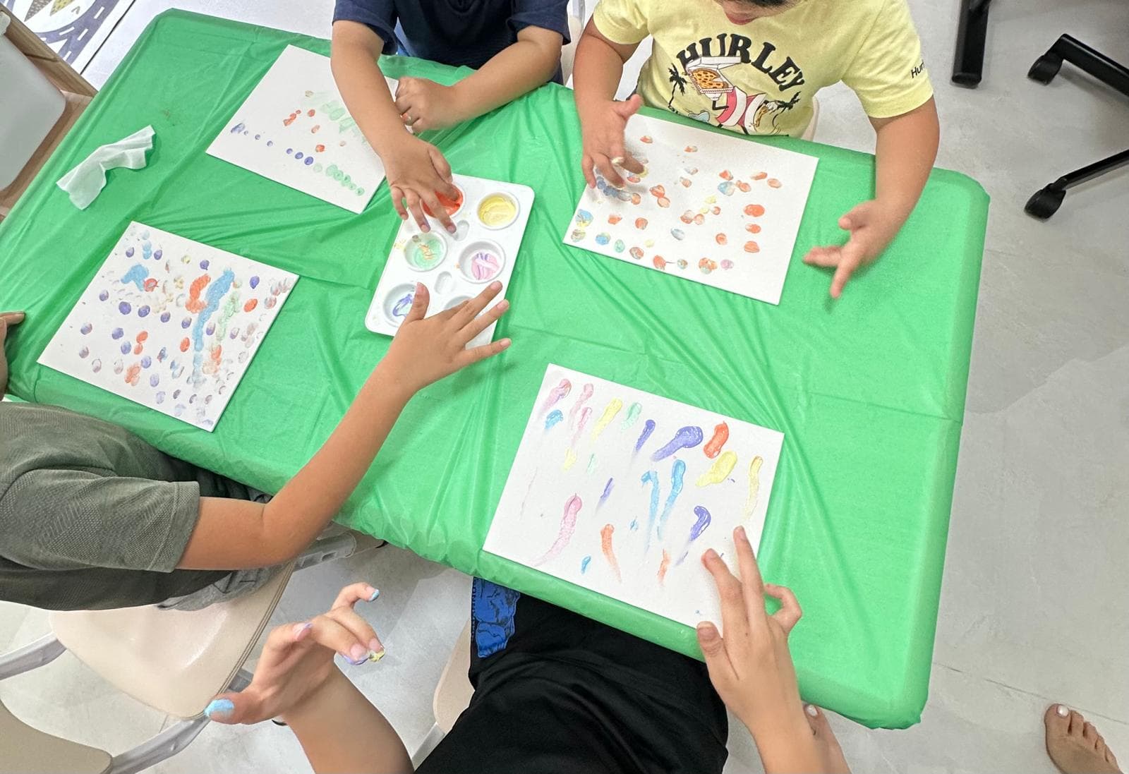 Children exploring colour together in a small-group finger-painting activity at Inclusive Kids Club